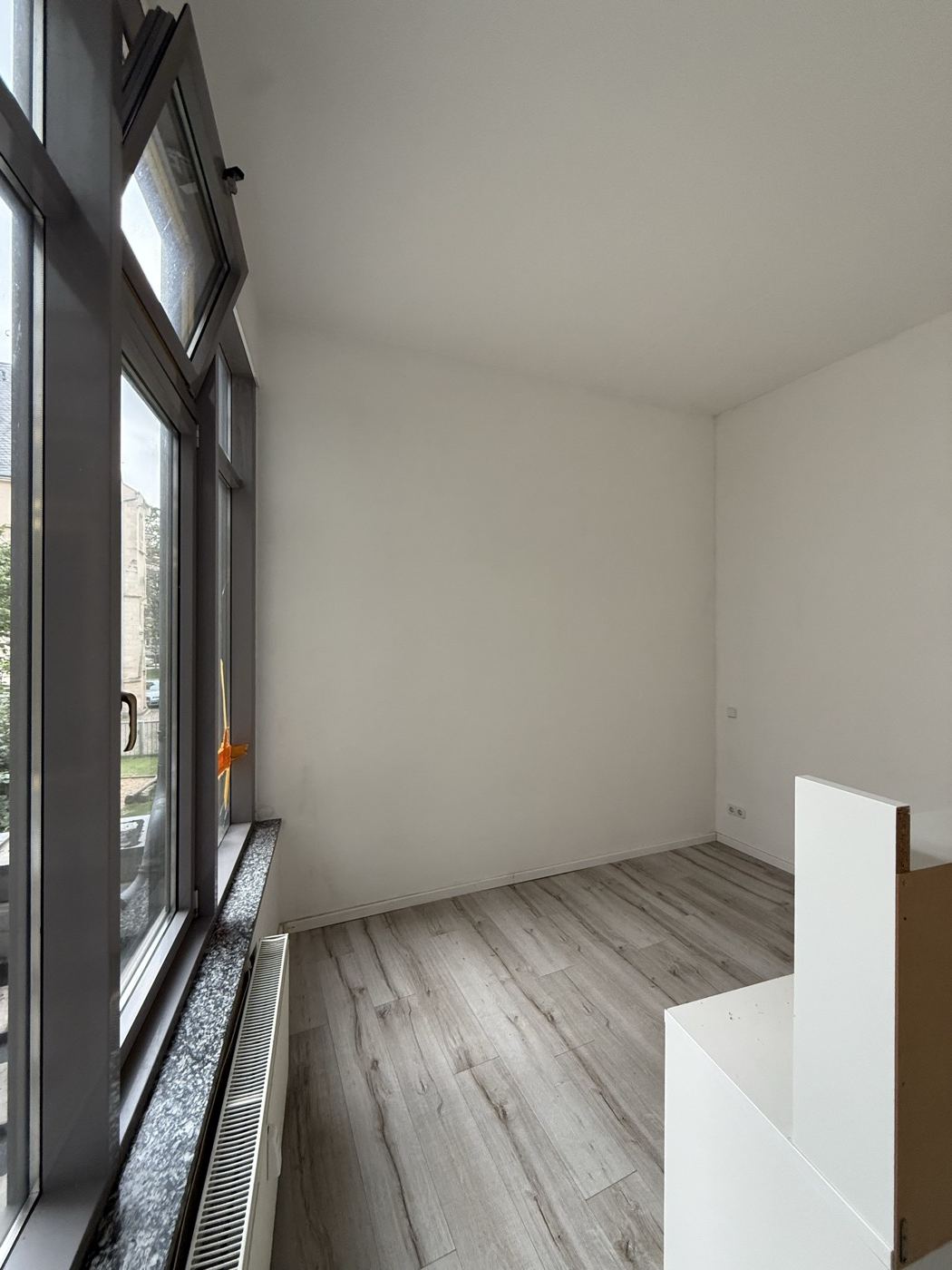 Übergabefertiges Zimmer mit Laminat und großem Fenster